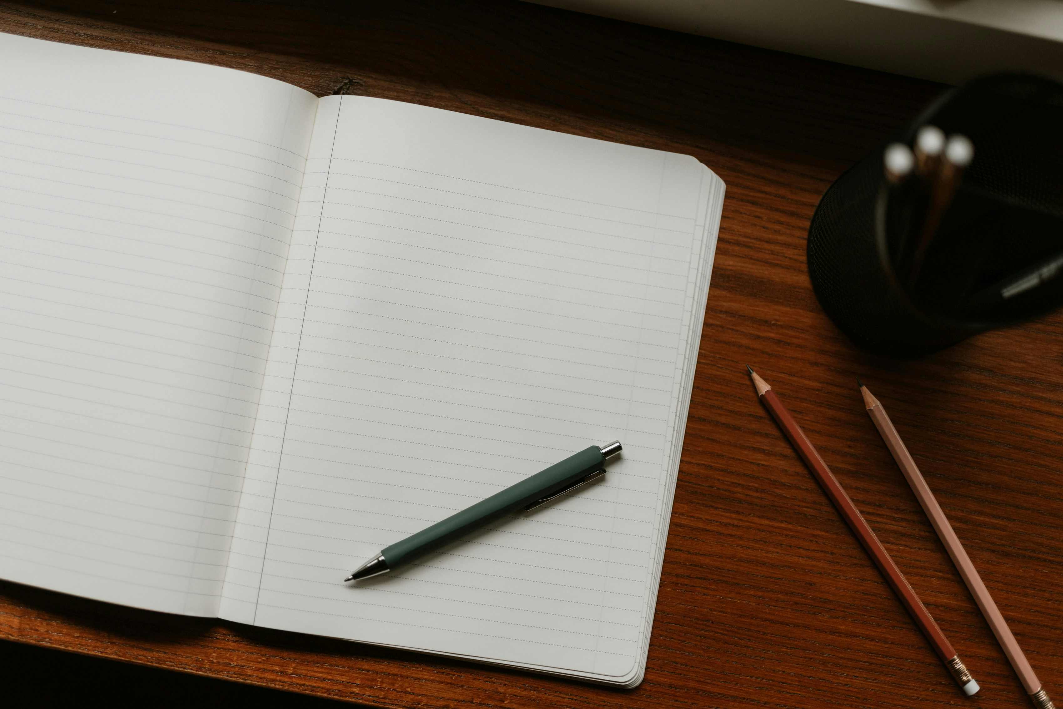 An open notebook and fountain pen on a wooden desk, the still moment before writing
