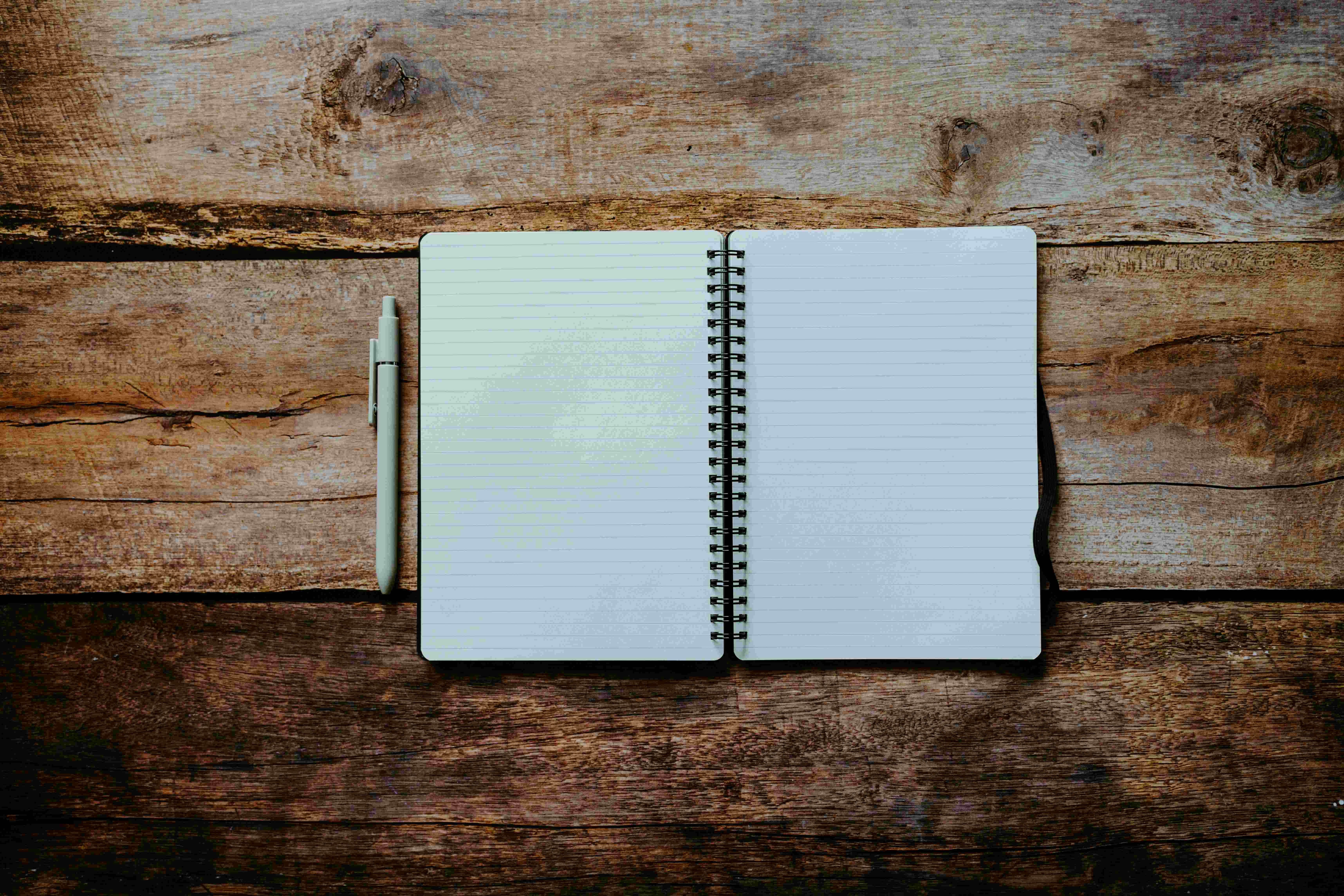 An open notebook with a pen on a wooden surface &ndash; the inquiry that precedes the work