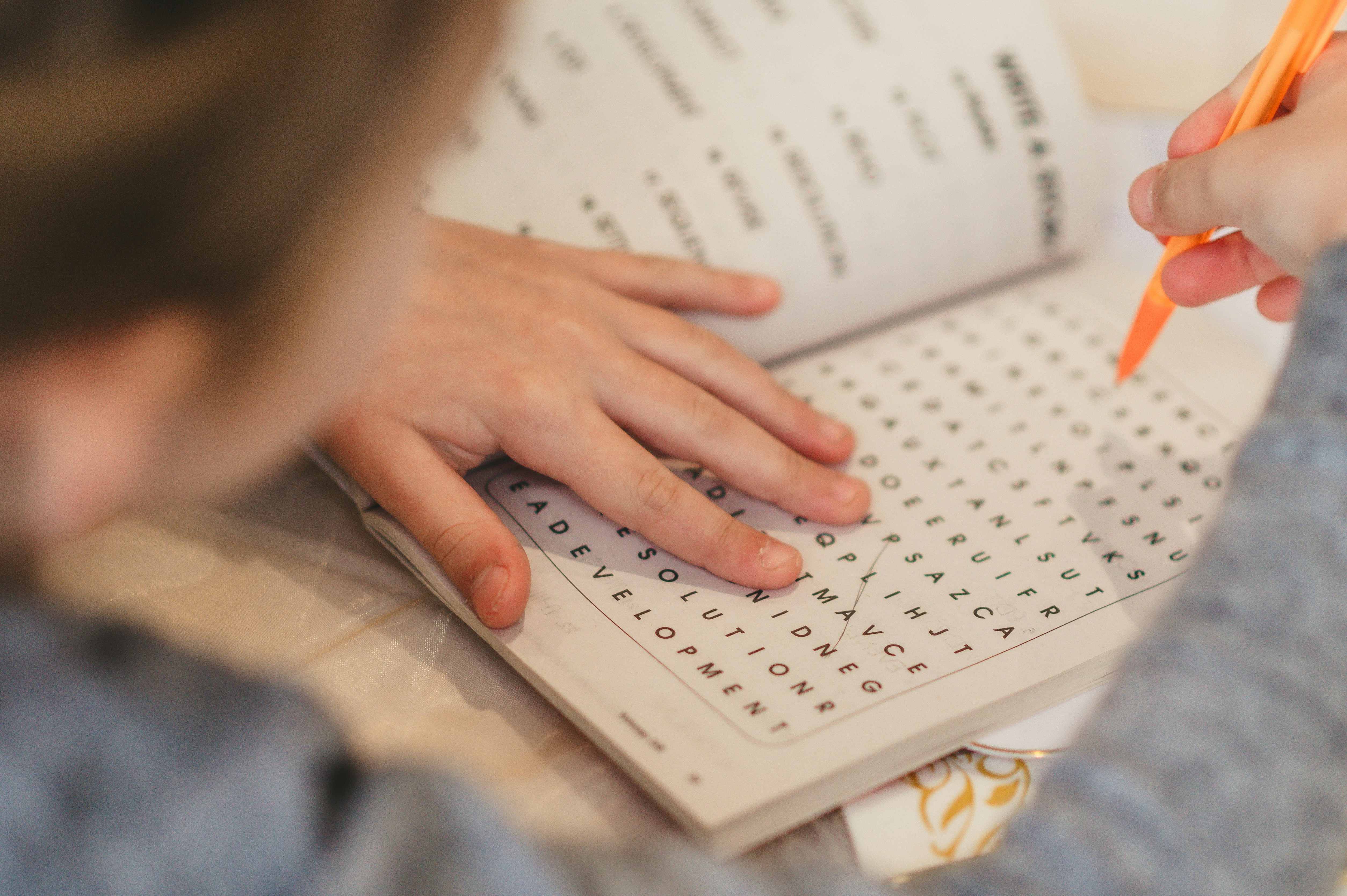 A child&rsquo;s hands at a wooden desk with an open exercise book and a pencil